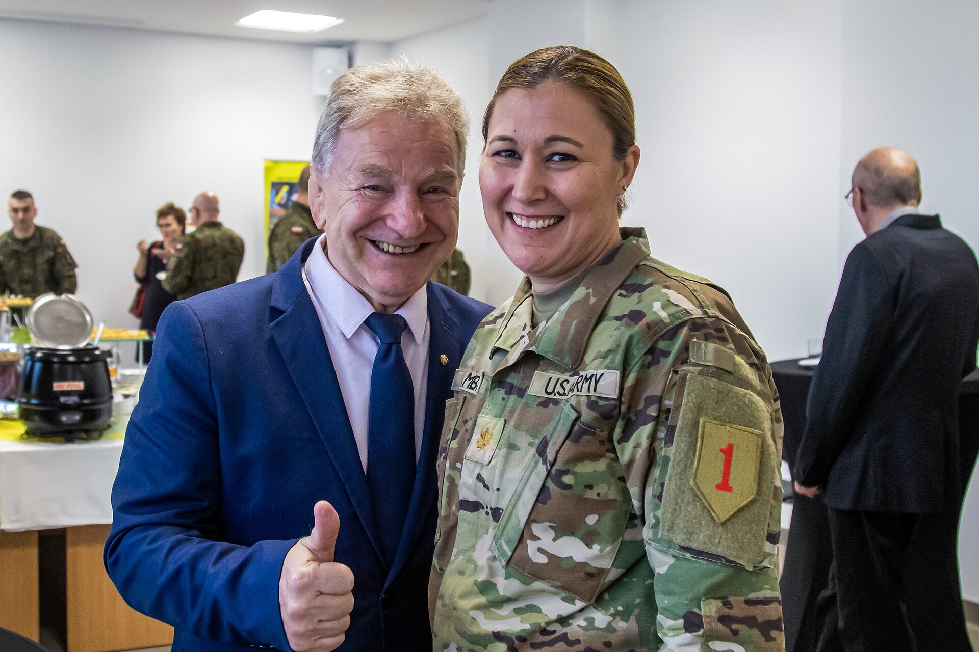 Homem de terno azul e mulher de farda militar sorrindo